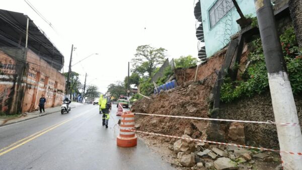 Rua interditada com cones e destroços após desabamento de muro provocado por chuva em Diadema