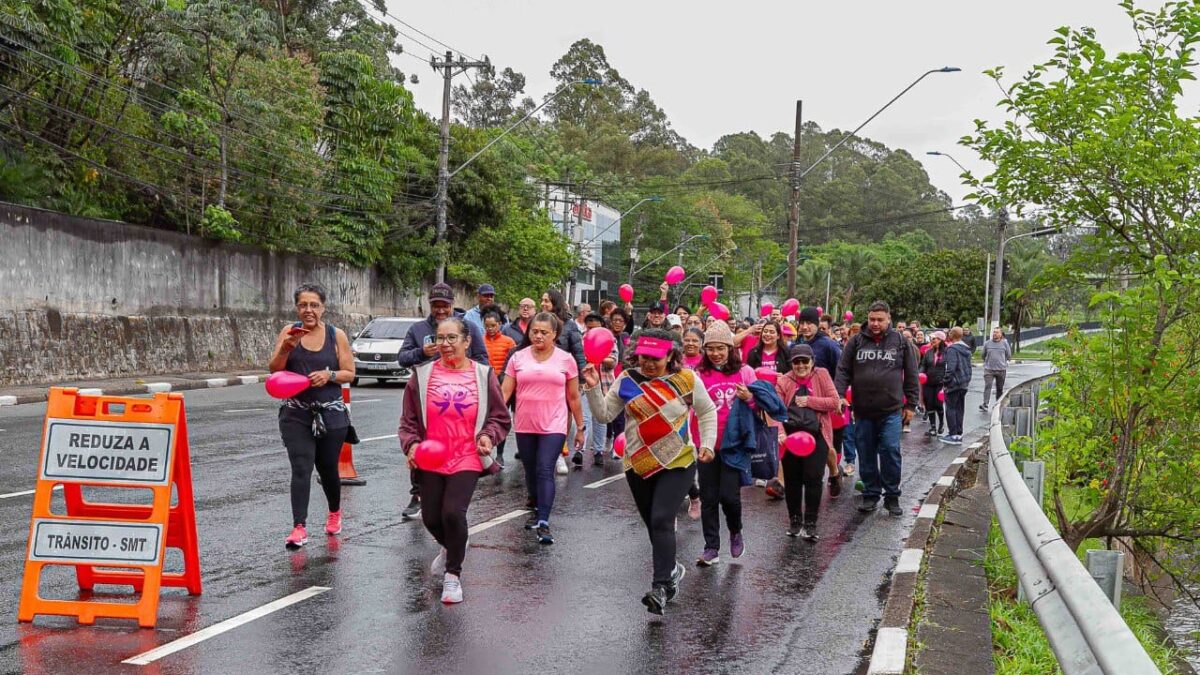 Participantes da caminhada do Outubro Rosa em Diadema, edição de 2025, com balões cor-de-rosa em via fechada ao trânsito