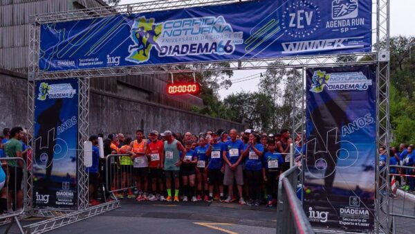 Largada da Corrida Noturna do aniversário de Diadema, edição de 2025, com corredores sob o pórtico de partida