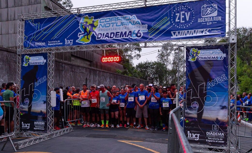 Largada da Corrida Noturna do aniversário de Diadema, edição de 2025, com corredores sob o pórtico de partida
