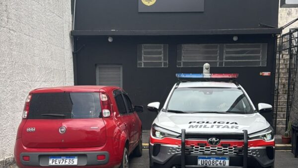 Fiat Uno vermelho apreendido ao lado de viatura da Polícia Militar em frente ao Distrito Policial (foto de divulgação)