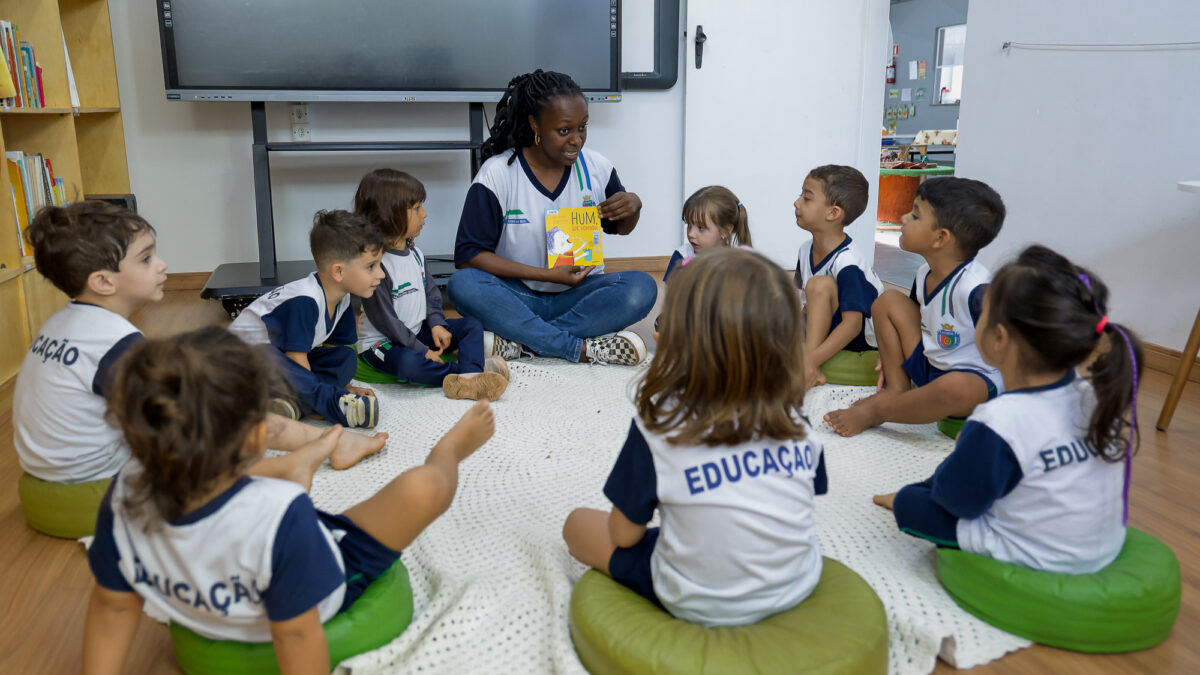 Professora lê livro para crianças sentadas em roda em escola municipal de Educação Infantil de São Caetano do Sul