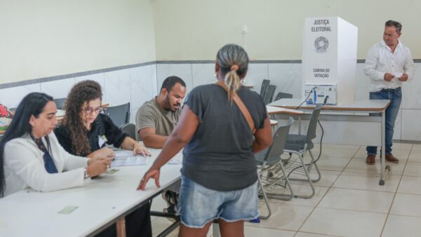 Mesários atendem eleitora em seção eleitoral de Brasília no primeiro turno, em 4 de outubro de 2026
