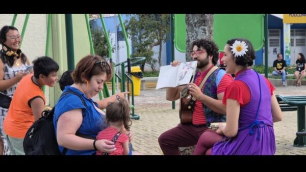 Artistas contam histórias com violão e livro para crianças e famílias em área de lazer