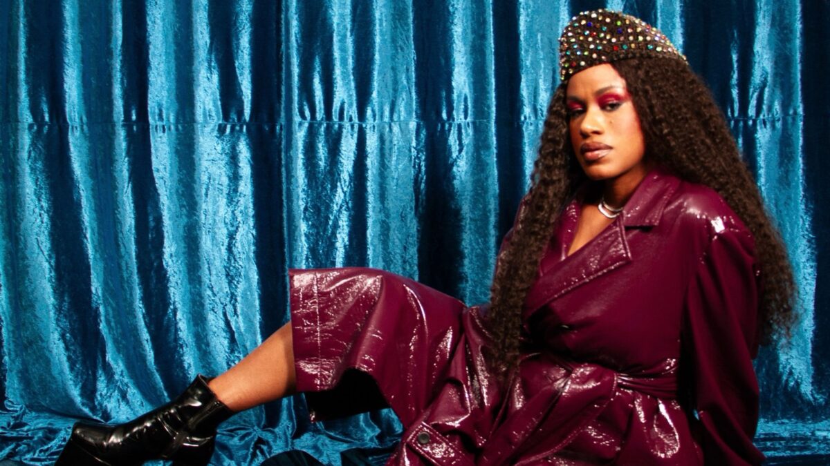 A rapper Stefanie posa sentada diante de cortina azul, em foto de divulgação do álbum BUNMI